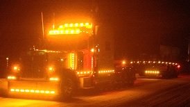 Semi-truck illuminated by numerous orange lights at night