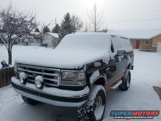 1995 Ford Bronco in driveway covered in snow, front end visible