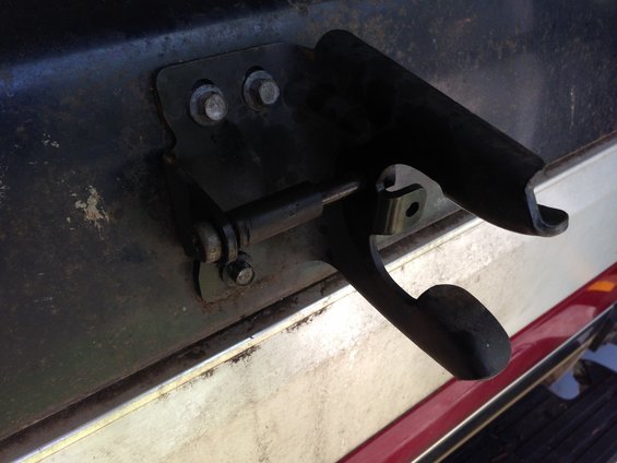Tailgate latch mechanism on a dark-colored vehicle with a red stripe