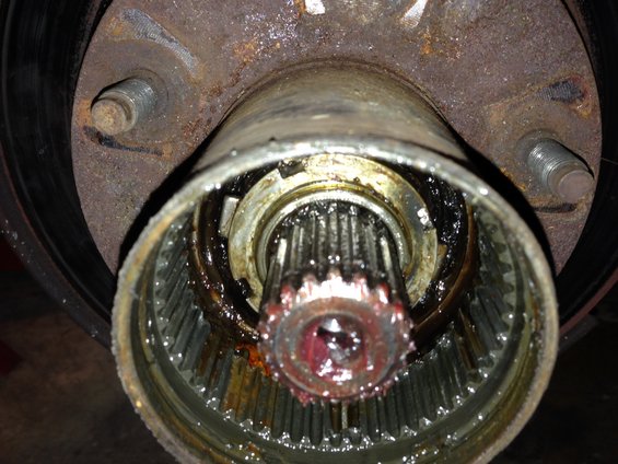 Close-up of a greasy, splined axle shaft inside a wheel hub assembly