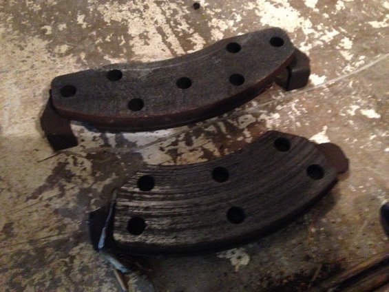 two worn brake pads on a concrete floor