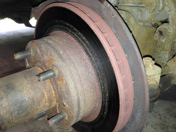 Rusty brake rotor with visible cracks and a corroded hub with five lug studs