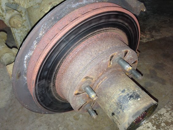 Close-up of a heavily rusted brake rotor and hub assembly with five lug studs