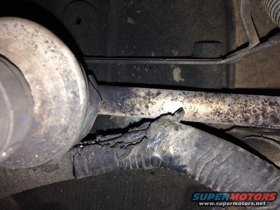 Damaged wire harness with frayed insulation, near a metal pipe