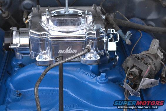 Demon carburetor mounted on a blue engine manifold with some wiring visible