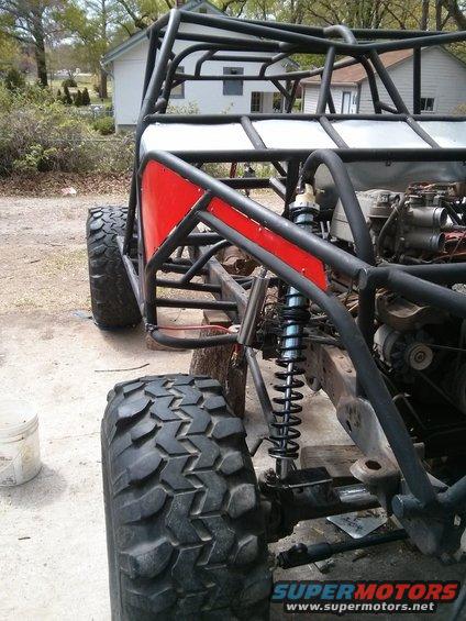 Off-road buggy chassis with large tires, suspension, and roll cage