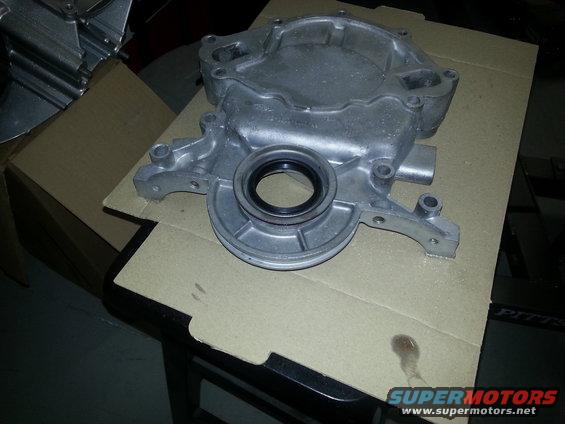 Engine timing cover with a seal. Cardboard box and stool in background