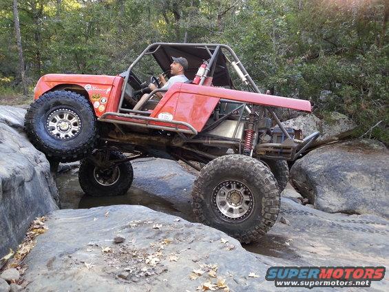 Red custom buggy with large tires on rocks