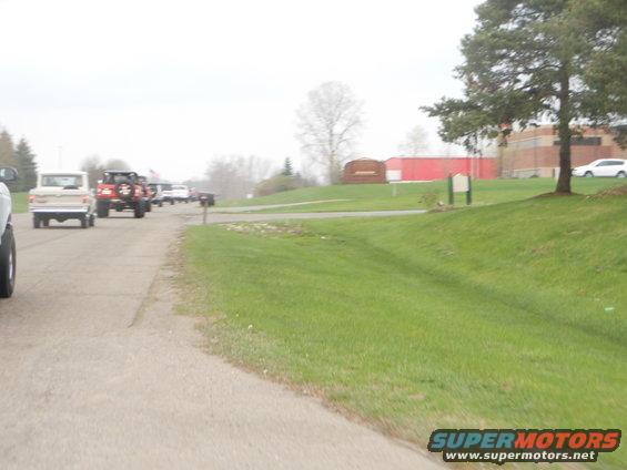Tan 1992 Ford Bronco driving on a road, rear view
