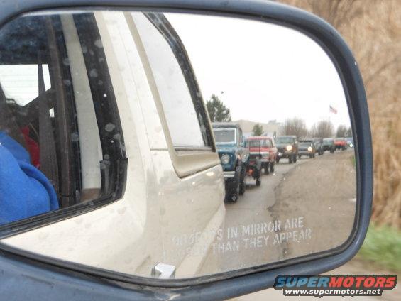 Reflection of multiple SUVs in a side mirror, with text 'Objects in mirror are closer than they appear'