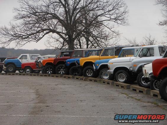 Line of vintage Ford Broncos in various colors, parked in a lot