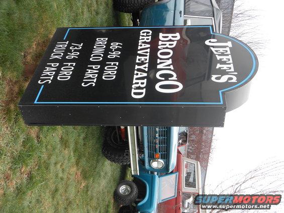 Sign for Jeff's Bronco Graveyard listing 66-96 Ford Bronco parts and 73-96 Ford truck parts, with blue and red Ford Broncos visible