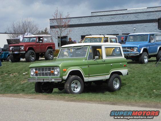 Green and white Ford Bronco in foreground, red and blue Broncos behind it