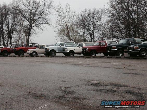 Side view of a line of Ford Broncos and F-Series trucks, one is light blue