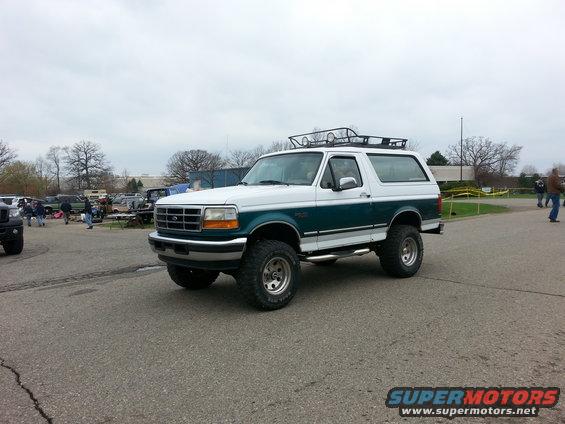White and teal Ford Bronco with roof rack, lifted on large tires