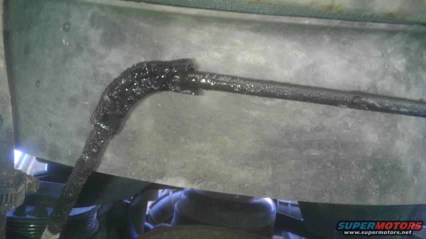 close-up of a greasy engine hose connected to a metal plate