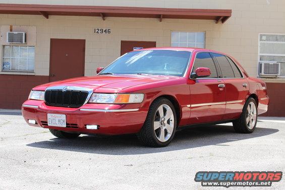 Red 2002 Mercury Grand Marquis sedan parked in front of a building