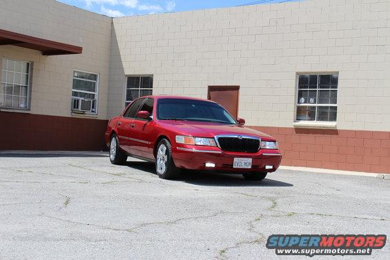 Red 2002 Mercury Grand Marquis parked in front of a brick building