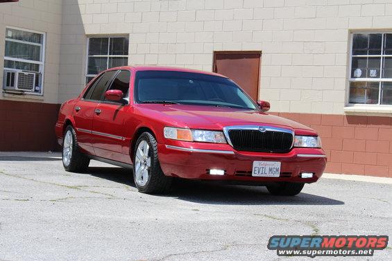 Red sedan parked on asphalt, front quarter view. License plate reads 'EVIL MGM'