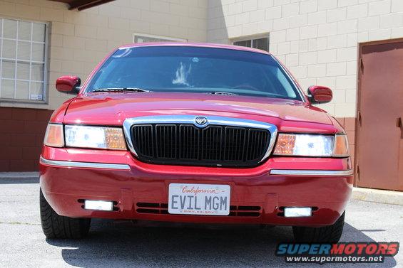 Front view of a red 2002 Mercury Grand Marquis with a black grille and a California license plate that reads 'EVIL MGM'