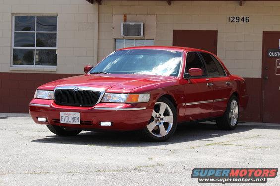 Red 2002 Mercury Grand Marquis parked in front of a building