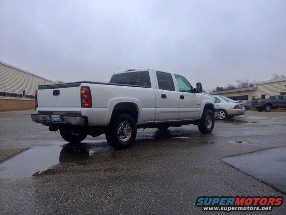 White 2006 Chevrolet Silverado 2500 crew cab pickup truck parked on wet asphalt