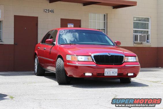 Red 2002 Mercury Grand Marquis with custom license plate 'EVIL MGM' parked outside