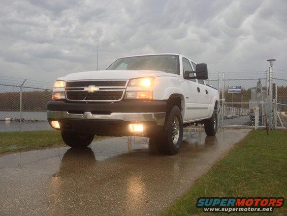 White 2006 Chevrolet Silverado 2500 pickup truck parked on wet pavement