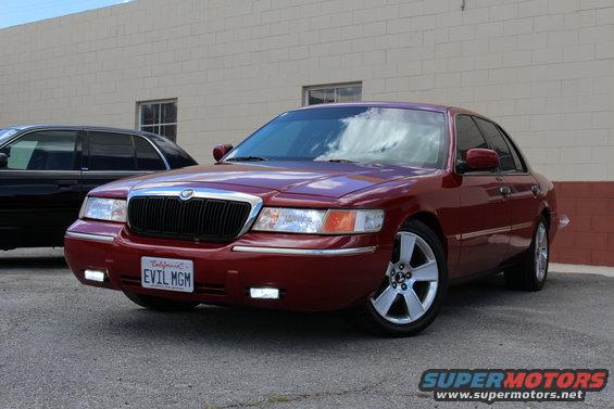 Red sedan with custom grille and aftermarket wheels. License plate reads 'EVIL MGM'