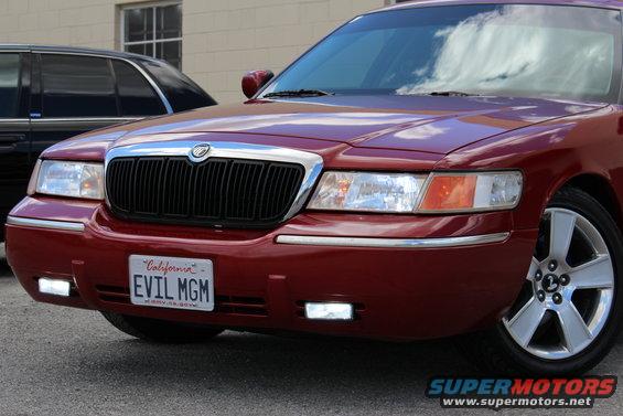 Red 2002 Mercury Grand Marquis front end with California plate EVIL MGM. Another dark vehicle is partially visible