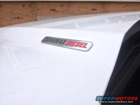 White vehicle fender with a Duramax Diesel badge. A black trim piece is visible on the right