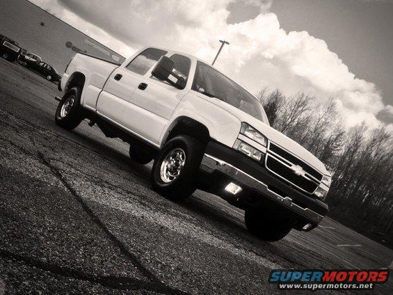 White 2006 Chevrolet Silverado 2500 pickup truck parked on asphalt with trees in background