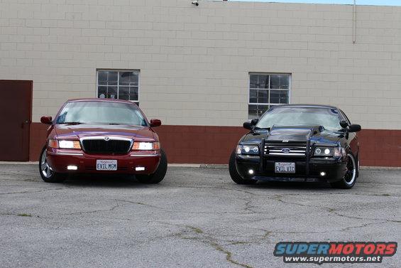 Red 2002 Mercury Grand Marquis and black modified sedan parked side-by-side