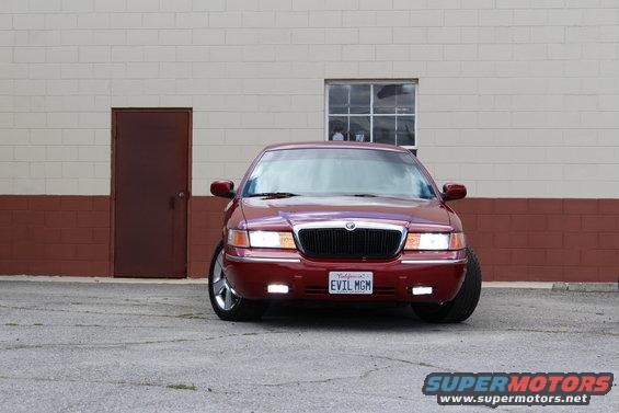 Red 2002 Mercury Grand Marquis parked in front of a brick and block building