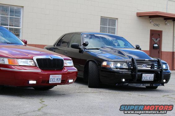 Red Mercury Grand Marquis and black modified sedan parked outside building