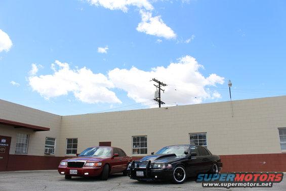 red sedan and black sedan parked outside a building under a cloudy sky