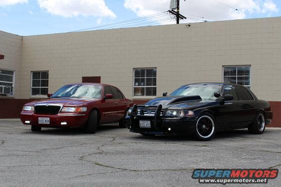 Red 2002 Mercury Grand Marquis and black modified sedan parked outside