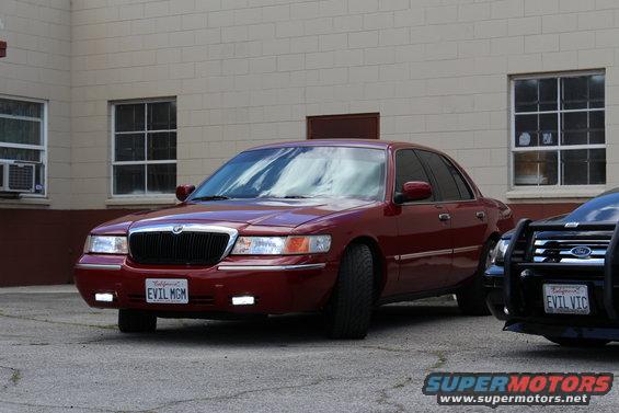 Red 2002 Mercury Grand Marquis sedan with custom license plate 'EVIL MGM'