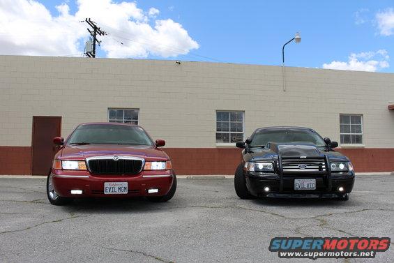 Red 2002 Mercury Grand Marquis and black modified car parked in front of a building