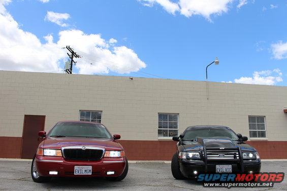 Red 2002 Mercury Grand Marquis with a license plate reading "EVIL MGM" parked next to a black car
