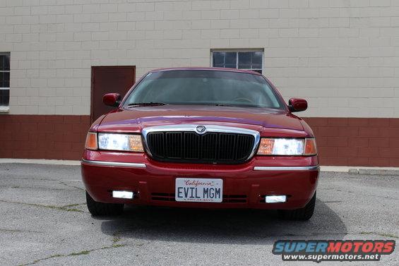 Front view of a red Mercury Grand Marquis with a black grille and a California license plate that says EVIL MGM