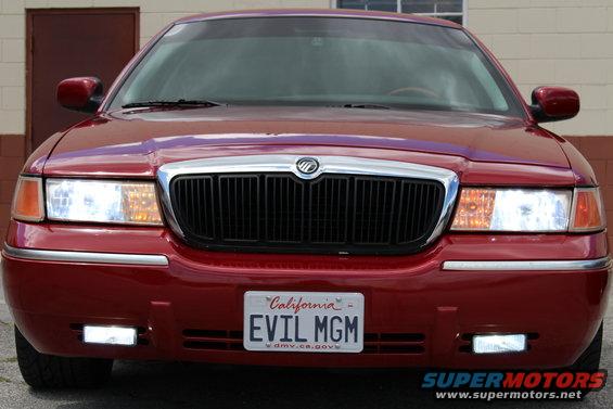 Front view of a red 2002 Mercury Grand Marquis with a black grille and California plates that say EVIL MGM