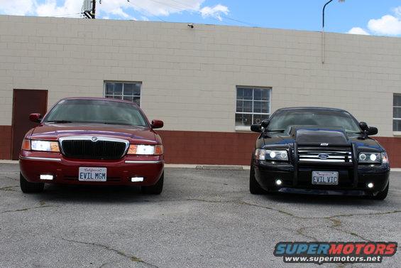 Red 2002 Mercury Grand Marquis with license plate "EVIL MGM" parked next to a black sedan