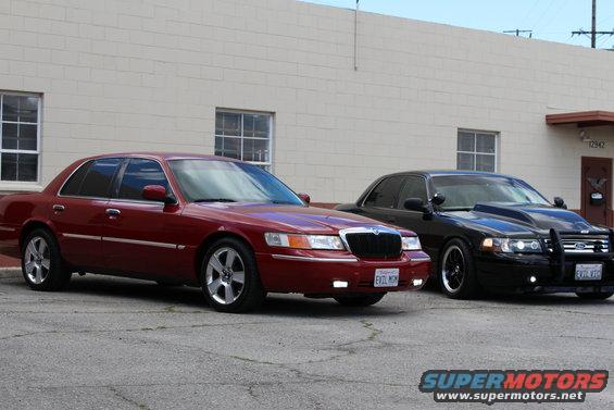 Red sedan parked next to a black sedan with a modified hood