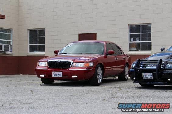 Red 2002 Mercury Grand Marquis parked next to a black police car