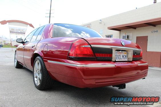 Red sedan parked outside a building. License plate reads EVIL MGM