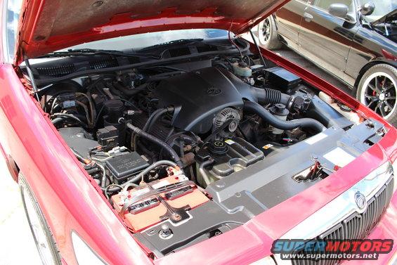Red car engine bay with Mercury badge on engine cover. 2002 Mercury Grand Marquis