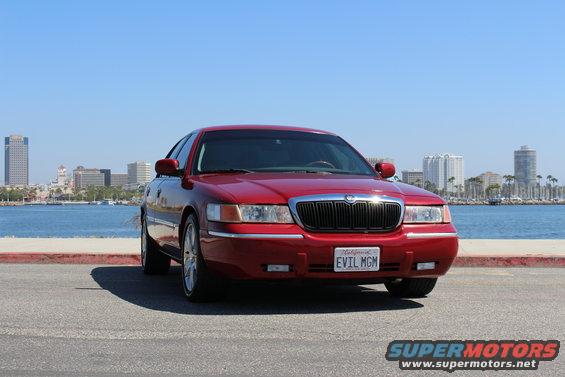 Red 2002 Mercury Grand Marquis parked by the water with city skyline in background