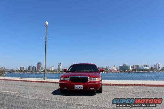 Red 2002 Mercury Grand Marquis with a custom license plate parked by the water
