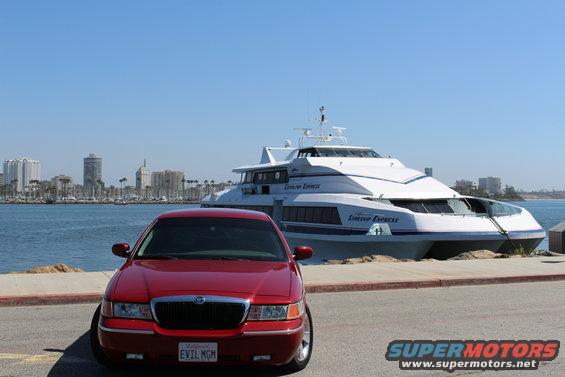 Red 2002 Mercury Grand Marquis parked with a large white passenger ferry in the background